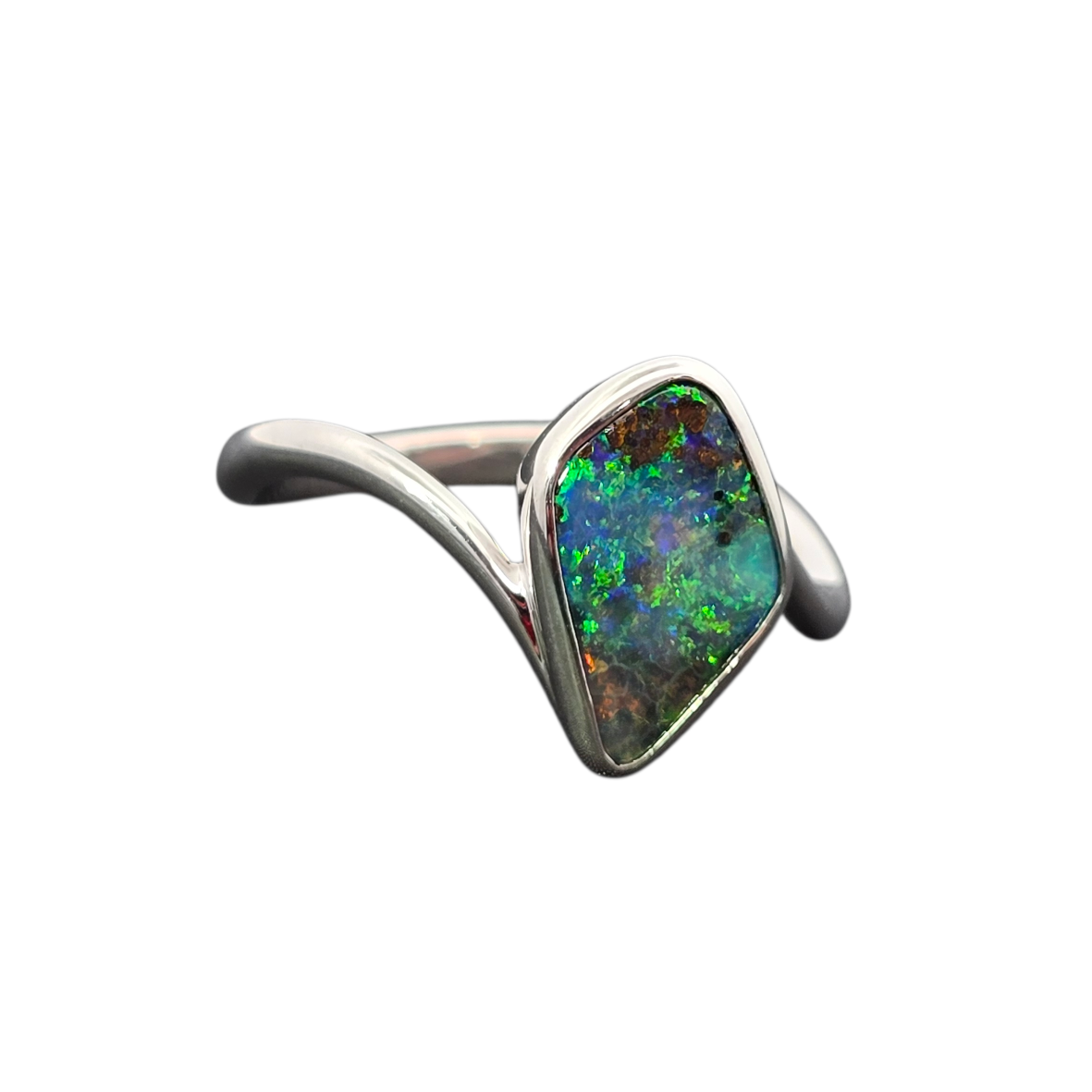 A silver ring featuring a large, irregularly shaped natural opal gemstone with vibrant green, blue, and orange flashes, set in a polished silver band on a plain white background.