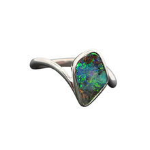 Load image into Gallery viewer, A silver ring featuring a large, irregularly shaped natural opal gemstone with vibrant green, blue, and orange flashes, set in a polished silver band on a plain white background.